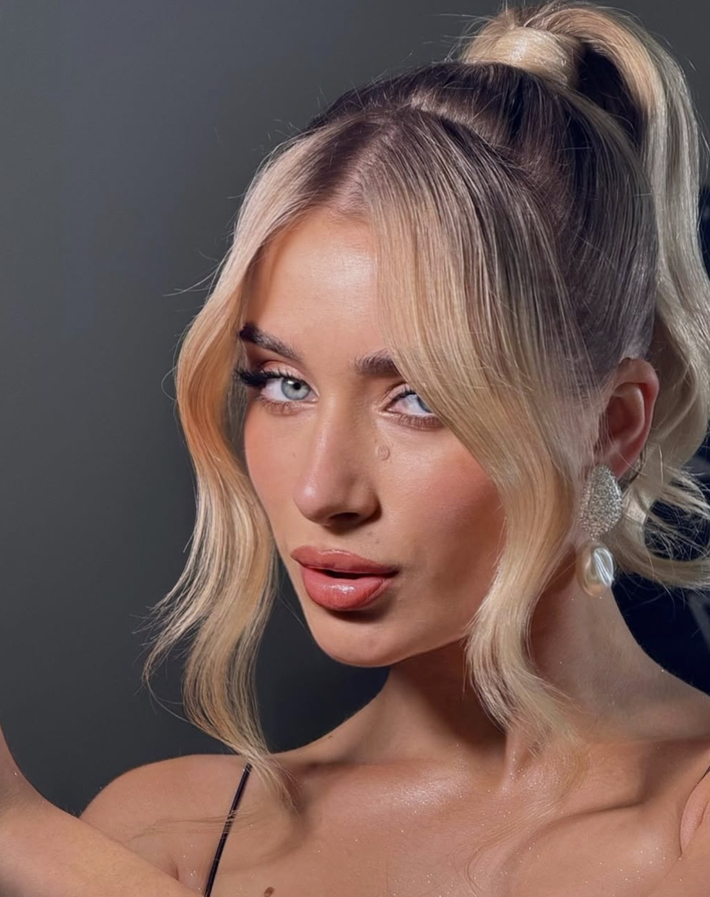 Luminous skin and glossy lip paired with a sleek ponytail