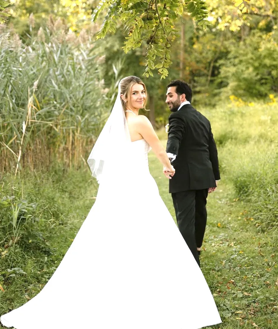 Bride and groom walking hand in hand through a golden-hour meadow