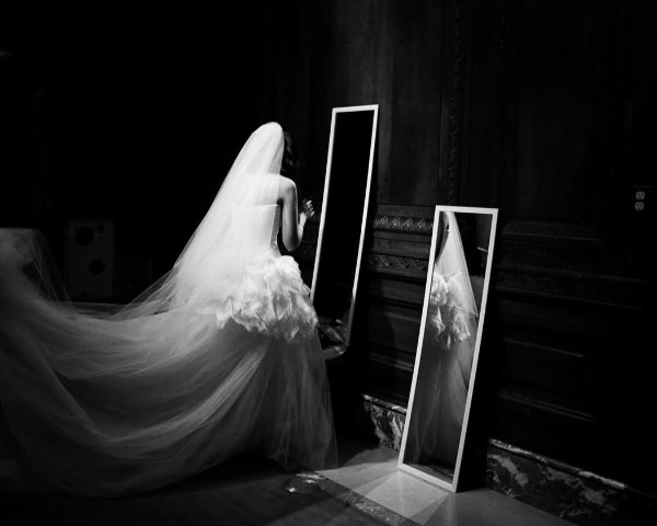 Bride admiring her reflection in full-length mirrors, black and white