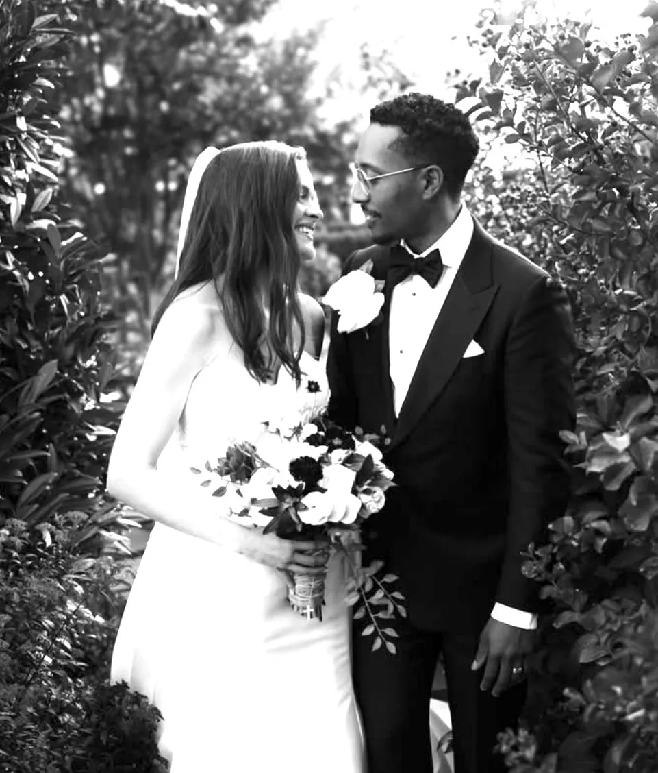 Newlyweds sharing a quiet moment in a lush garden, black and white